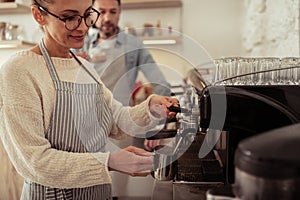 Woman frothing milk by the coffee machine.