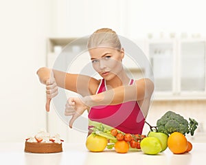 Woman with fruits showing thumbs down to cake