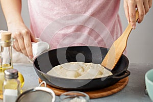 Woman frying mexican flatbread on cast iron pan.