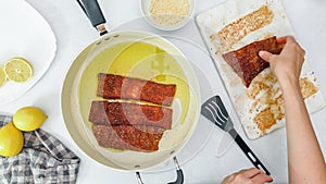 Woman frying salmon pieces marinated in smoked paprika, close up preparation process