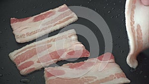 Woman frying slices of bacon on pan for pasta, 4k video