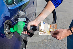 Woman fueling car tank and holding euro money photo