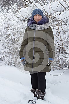 Woman full length in the snow,a beautiful woman standing in the snow in a green jacket and a knitted hat