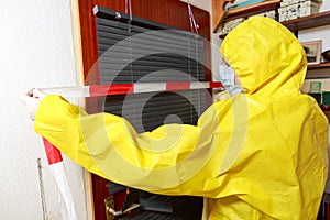 Woman in a full protective suit secures with a barrier tape