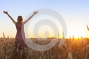 Woman full of vitality embracing sunrise in wheat field photo