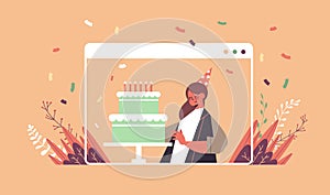 Woman in funny festive hat celebrating online birthday party girl in computer window blowing cake candles