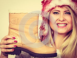 Woman in furry winter hat holding beige boots