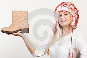 Woman in furry winter hat holding beige boots