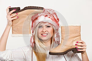 Woman in furry winter hat holding beige boots