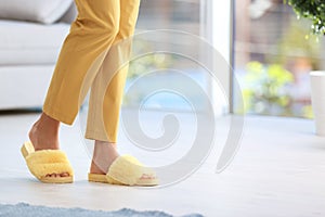 Woman in fuzzy slippers at home, space for text