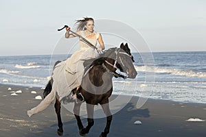 Woman on galloping horse on beach