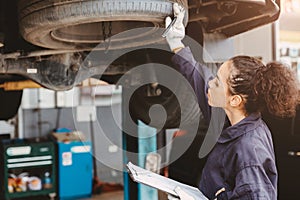 Woman garage worker maintenance checklist at automobile service center, Female in auto mechanic car technician work service check