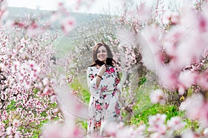 a woman in the garden of flowering peach trees in the spring