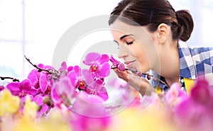 Woman in the garden of flowers, touches and smells orchid