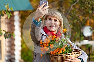 Woman in the garden harvests vegetables, fruits on the background of the house and trees