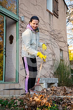 Woman gardening, collecting autumn leaves with a rake