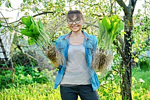 Woman in gardening gloves holding bush of hosta plant with roots for dividing planting