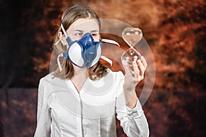 Woman in a gas mask holding a large glass sand timer . Coronovirus Quarantine, Stay Home Concept. Covid-19 pandemic