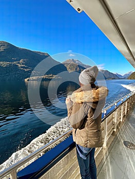 Woman gazes at the breathtaking Doubtful Sound scenery from a cruise in South Island, New