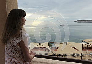 A Woman Gazes Down from Her Seaside Resort Balcony photo