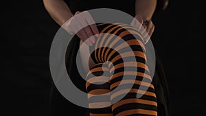 Woman gently corrected striped orange stockings on legs.