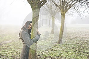 woman gently embraces the trunk of a tree symbolizing lifeblood, abstract concept