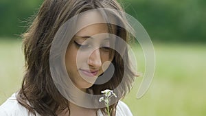 Woman gently looks at flower feeling oneness with nature, slow motion outdoors