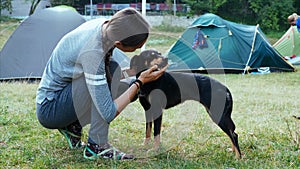 Woman is gently stroking mongrel dog at campfire