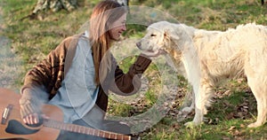 Woman gently stroking white dog together around fire place.real friends people outdoor camping tent vacation in autumn