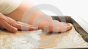 Woman gently unfurl bread dough onto prepared baking sheet