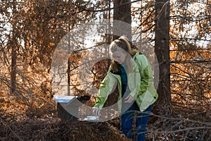 A woman geocaching. Women in woods find geocache container.
