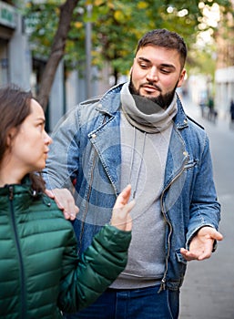 Woman gesturing stop to man flirting with her on street