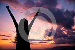 Woman gesturing success - silhouette over evening sky