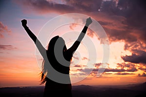 Woman gesturing success - silhouette over evening sky