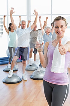 woman gesturing thumbs up with people stretching hands fitness studio
