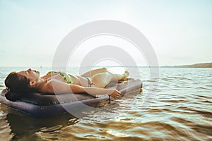 Woman get tan while lying on Inflatable mattress