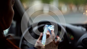 A woman gets into the car and turns on the Navigator on her smartphone on a rainy evening