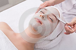 Woman gets face mask by beautician at spa