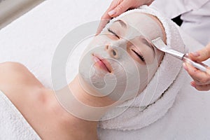 Woman gets face mask by beautician at spa