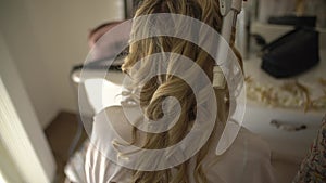 A woman gets her hair done and curls her hair in preparation for the wedding.