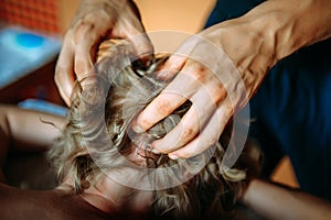 Woman gets professional head massage, close-up. Men`s hands doing massage of the scalp