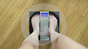 A woman gets on the scales and sees her weight of 103.5 lb. First-person view