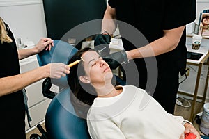 A woman getting botulinum toxin or fillers on her forehead and face by a doctor and nurse practitioner