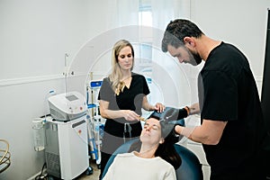 A woman getting botulinum toxin or fillers on her forehead and face by a doctor and nurse practitioner