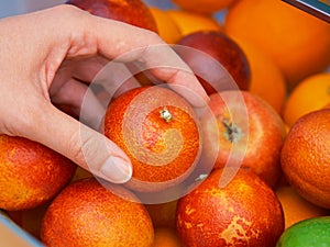 A woman getting a cara cara orange from a fridge compartment