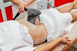 Woman getting cryolipolysis fat treatment in professional cosmetic cabinet