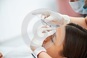 Woman getting a dermal filler injection into the glabellar line