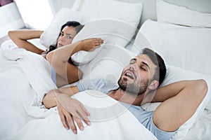 Woman getting disturbed with man snoring on bed