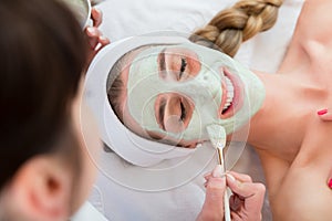 Woman getting facial care by beautician at spa salon