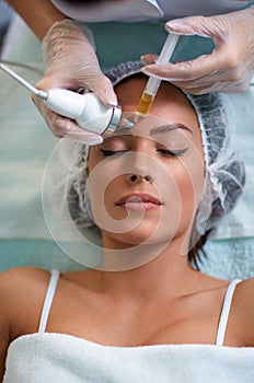Woman getting facial hydration of the skin with oxygen treatment at cosmetic clinic